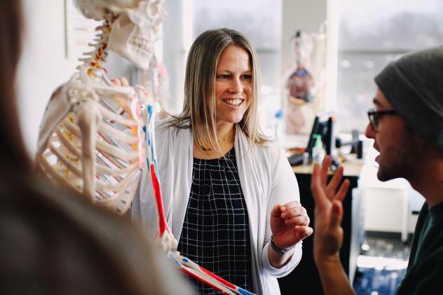 Teacher in lab coat next to skeleton